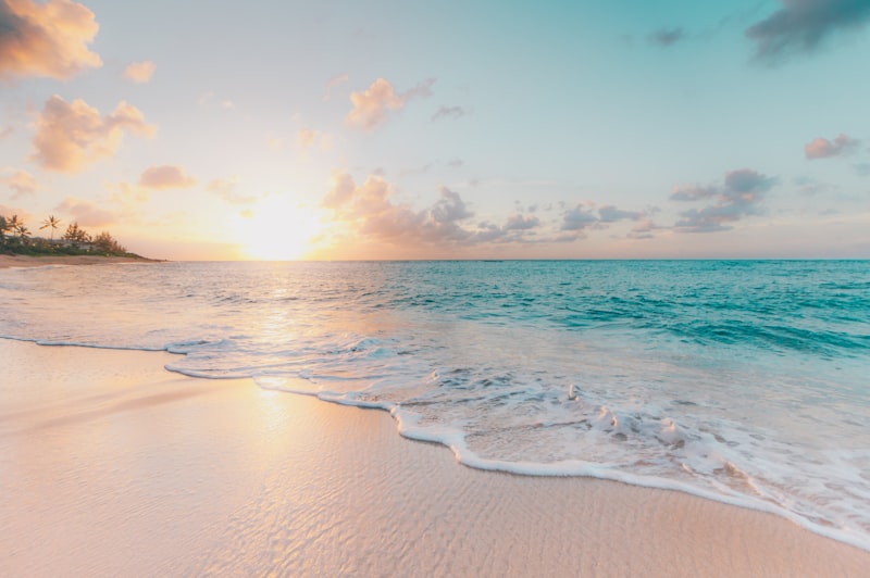 Tropical beach at sunrise with gentle turquoise waves on golden sand